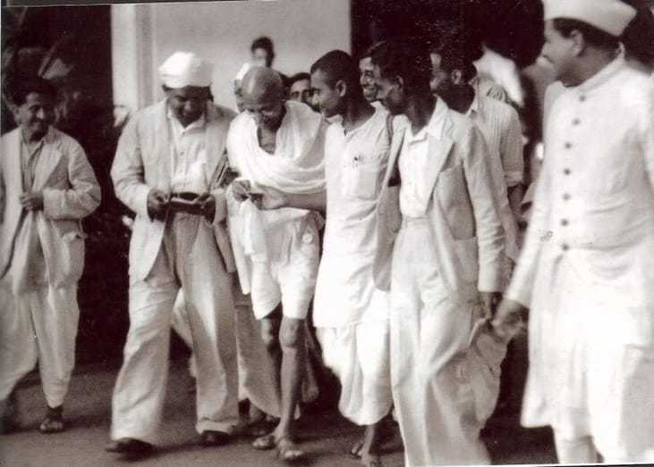 Gandhi walking with Kanu Gandhi (right) and others. Mumbai. Maharashtra. India. September, 1944.