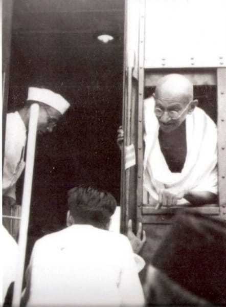 Gandhi during a train journey in 1945. Left his secretary Pyarela.
