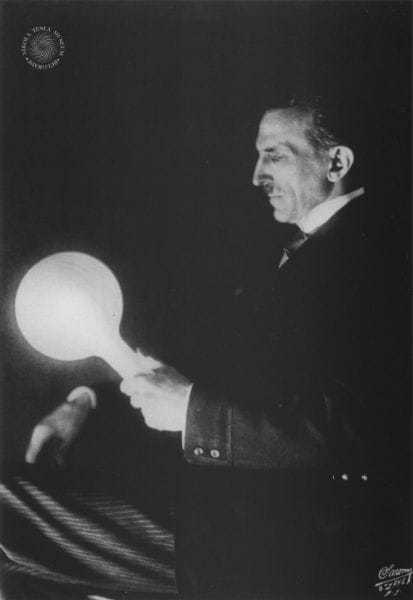 One of Dr. Tesla's striking experiments. A blare of light produced in a filamentless bulb by wireless power transmitted from a loop carrying terrific currents oscillating eighty million times per second.