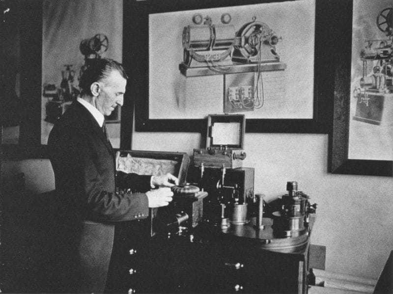 Tesla in his office in 1916, demonstrating an electrical apparatus.