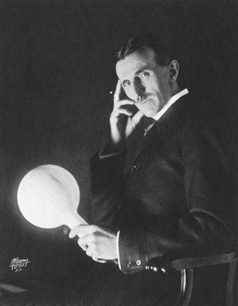 Tesla holding a gas-filled phosphor coated wireless light bulb which he developed in the 1890's, half a century before fluorescent lamps come into use. Published on the cover of the Electrical Experimenter in 1919.