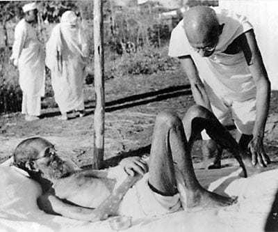 Gandhi giving massage, 15 min. daily, to a leper patient, the Sanskrit scholar Parchure Shastri, at Sevagram Ashram. 1940.