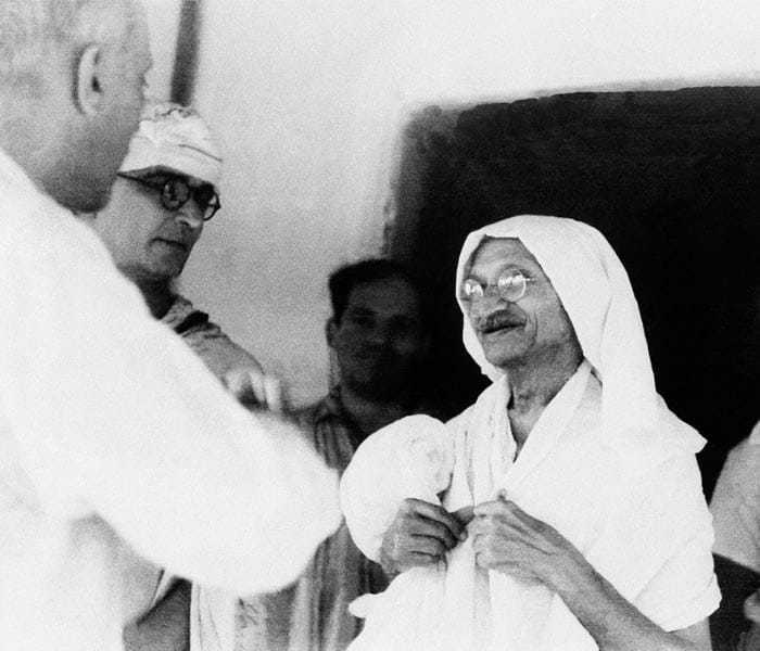 Mahatma Gandhi chatting with Jawaharlal Nehru in the doorway of the house where they conferred in Wardha, Bombay, September 9, 1942. At far left is Gandhi's secretary, Mahadev Desai.