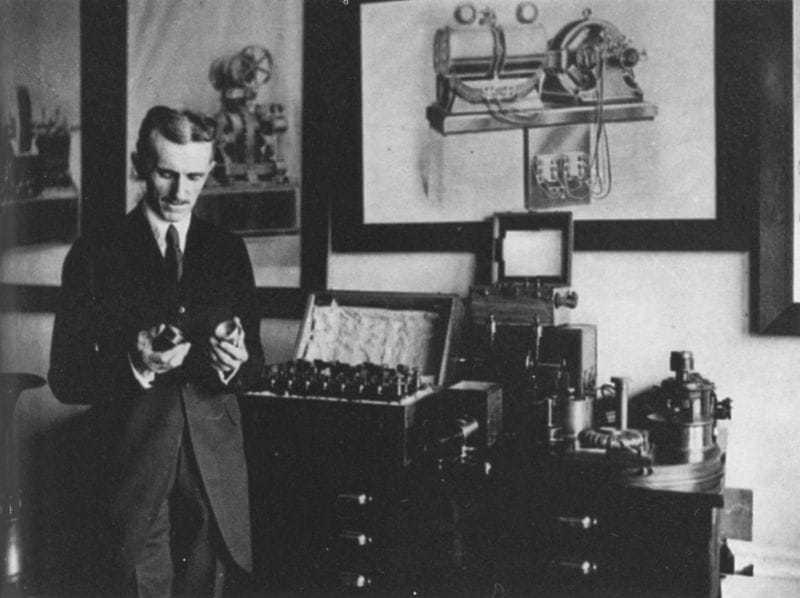 Tesla in his office in 1916, demonstrating an electrical apparatus.