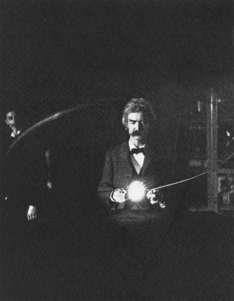 The high-voltage high frequency current is being passed through the human body to bring the lamp to incandescence. Mr. Samuel Clemens (Mark Twain) is holding the loop over the resonating coil. Tesla is at the switch in the background. (From a flash-light photograph.)