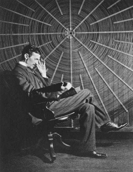 Nikola Tesla, with Roger Boskovich's book, “Theoria Philosophiae Naturalis,” in front of the spiral coil of his high-frequency transformer at East Houston St. 46, New York.